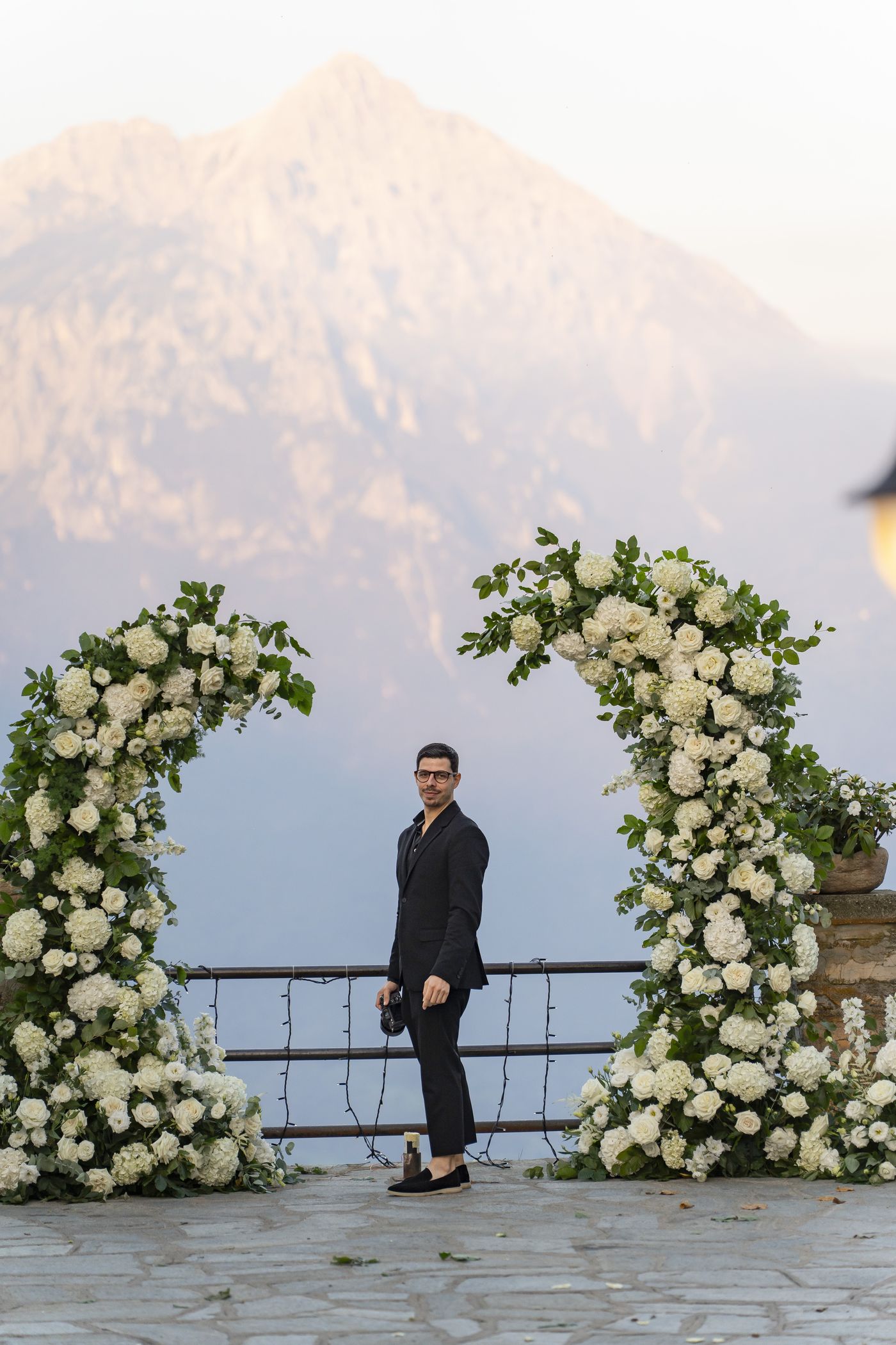 Diogo junto a um arco floral, com a serra ao fundo